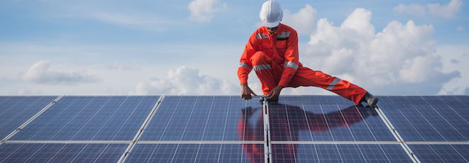 man on roof installing energy efficient solar panels